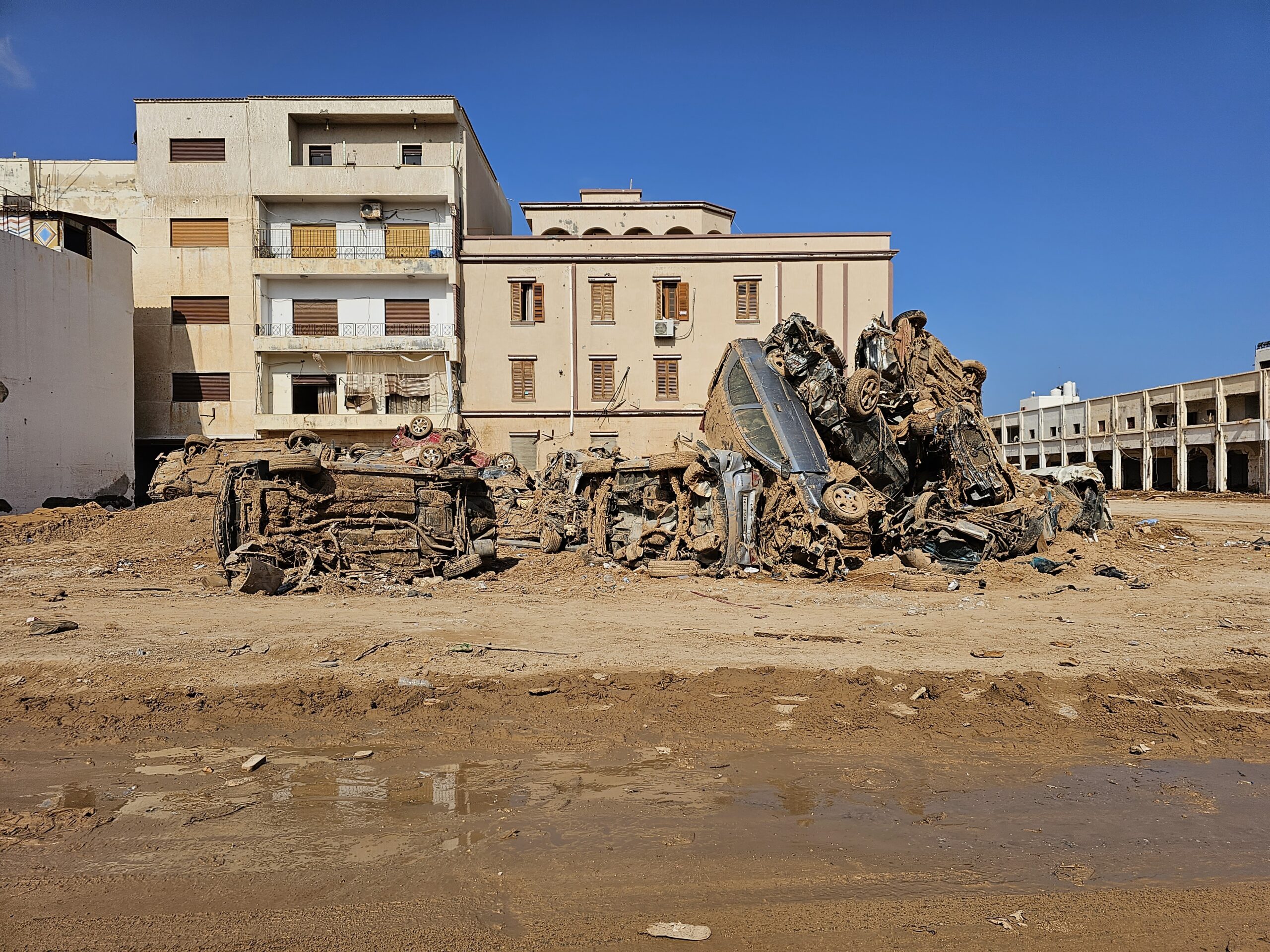 A pile of destroyed cars covered in mud from floodwaters sits on the side of the road in Libya.