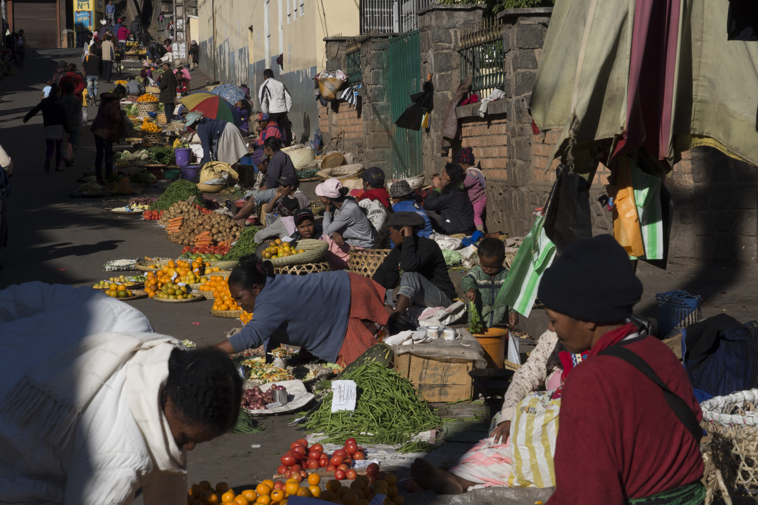 A street in Antananarivo, Madagascar with people sitting on the ground selling fruit.